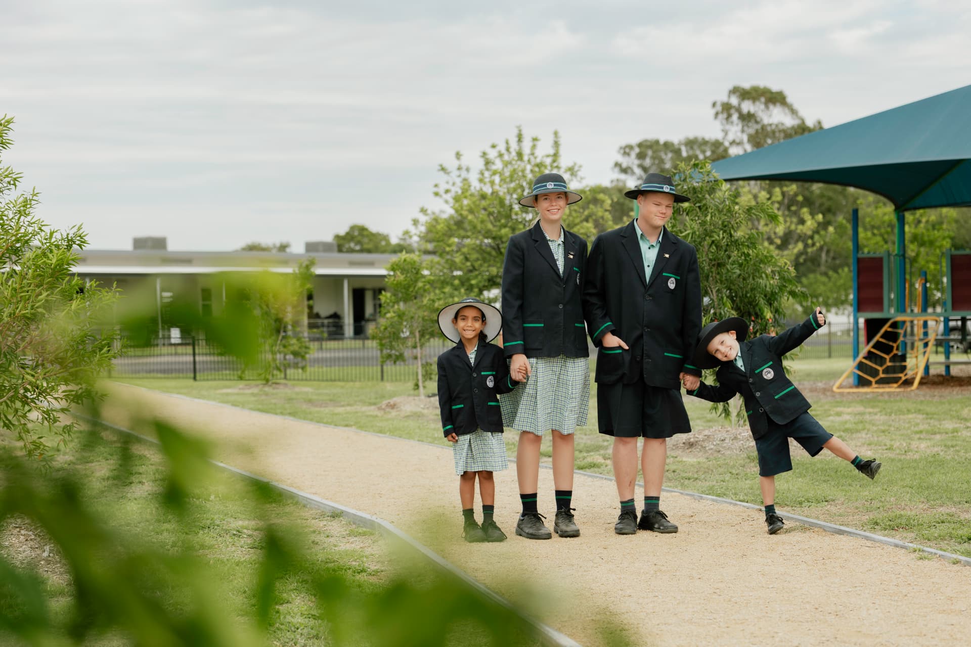 Four Border Rivers students of different year levels standing together on a path in the College grounds