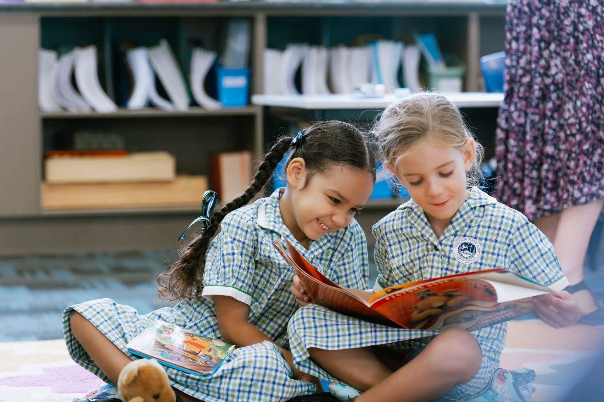 Two Border Rivers Prep students sitting together on the classroom floor, sharing a picture book